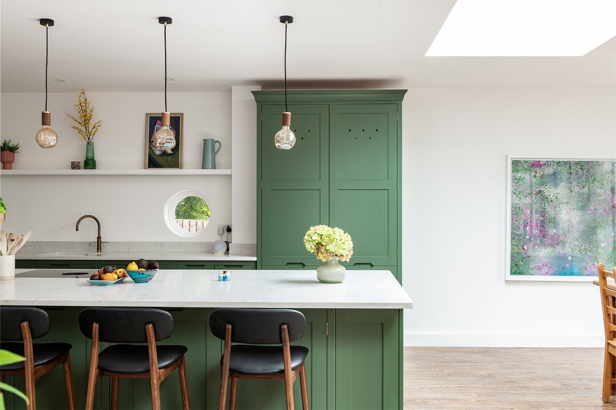 A green kitchen design with crisp white walls, neutral work surfaces, and minimalist decor.