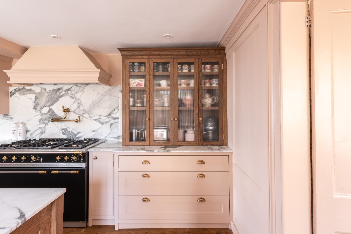 View of the cooking run with a a wood breakfast cupboard with two sets of fluted glass bi-fold doors and integrated lighting.