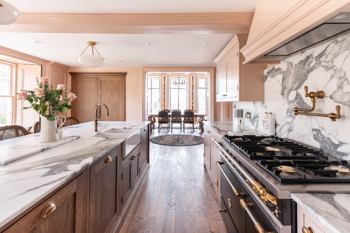 A cooking run sat opposite an island with a range cooker and statement marble surfaces.