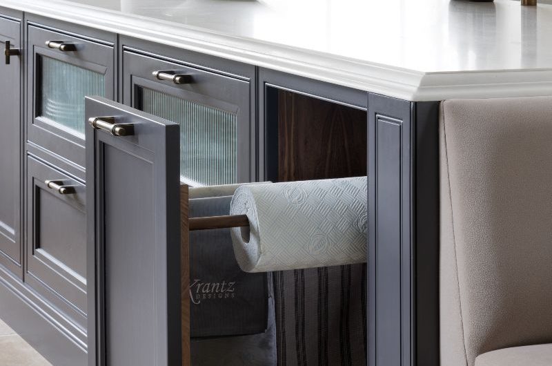 A Shaker island design painted in a dark blue with white countertop, reeded glass drawers, and pull-out storage drawers.