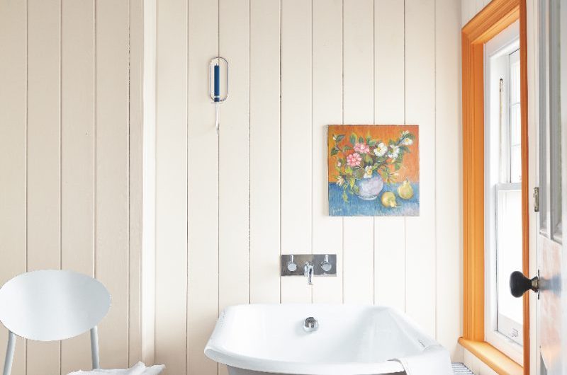 A classic scheme with wood floor, white panelling, and a bold blue ceiling, with a slipper bath near the window.