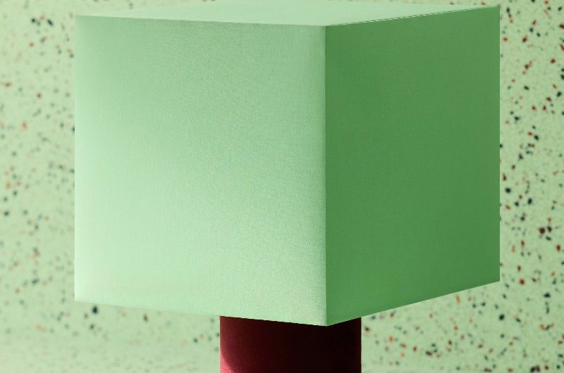 Closeup at a mint bedside table with a round burgundy base with terrazzo background.