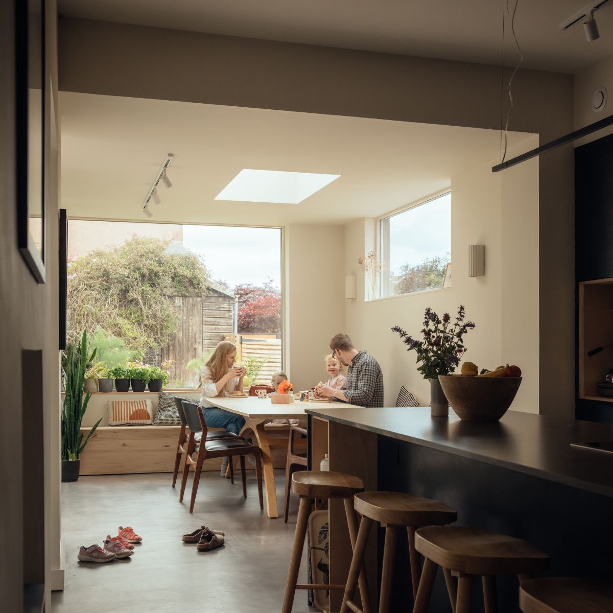 An open-plan living space flooded with light through wide windows and skylights.