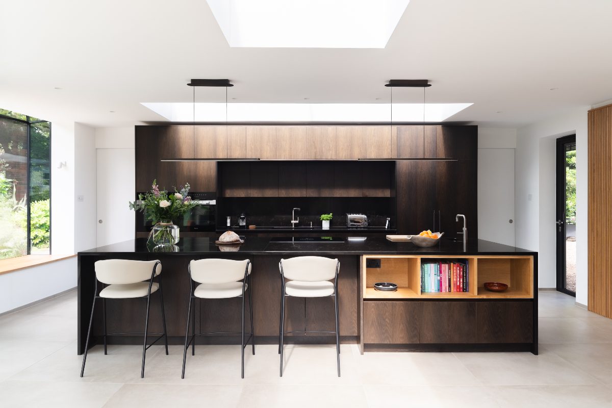 Dark wood kitchen design with floor-to-ceiling cabinets, a central island with seating, skylights and stone flooring.