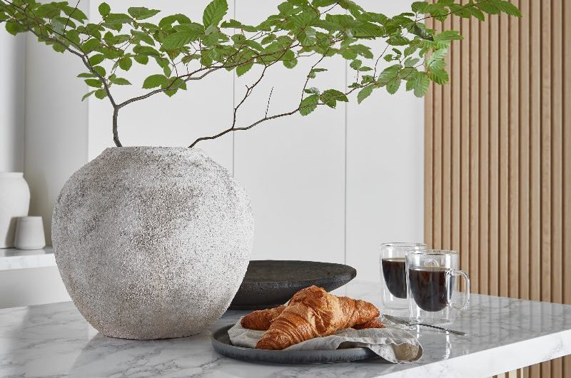 Closeup at a kitchen island with reeded panelling and stone worktop with minimalist Japandi decor.