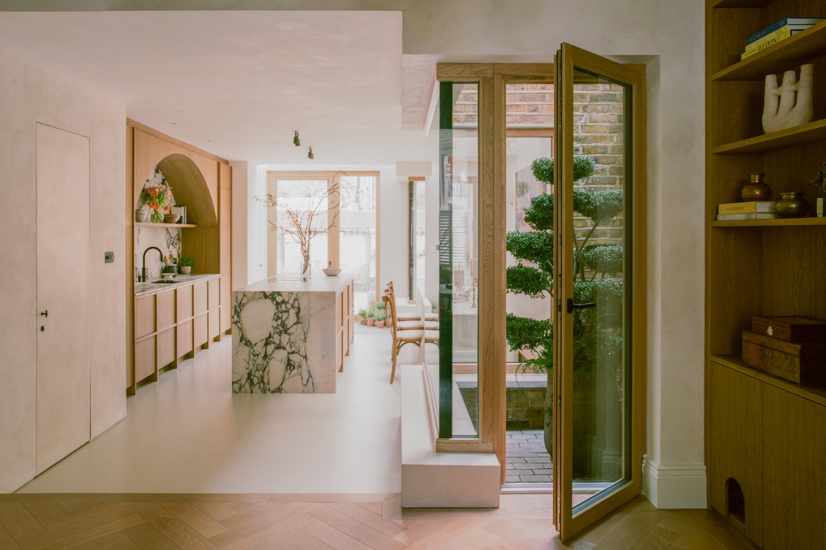 An open-plan kitchen-diner with wood cabinetry, a central marble island, and an internal courtyard.