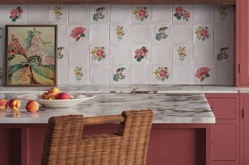 A burgundy kitchen design with checkerboard flooring, floral patterned wall tile splashback and daring floral wallpaper above it.