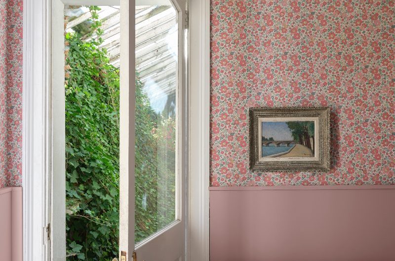 A boot room with pink panelling and floral wallcoverings.