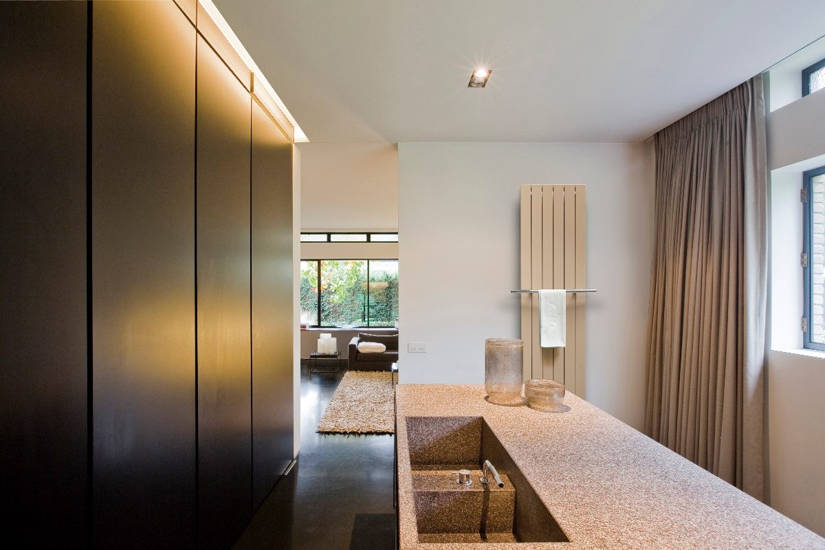 A cooking area with terrazzo unit inn the centre, tall furniture on the left, and a neutral radiator.