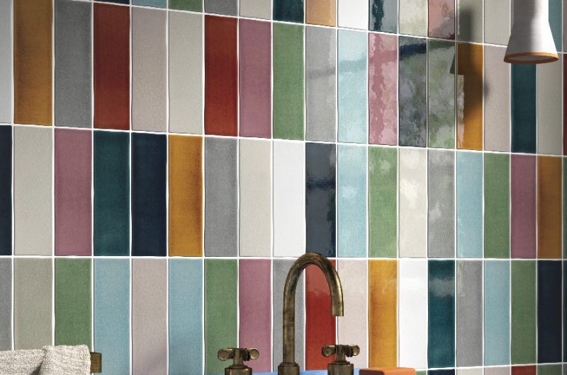 A playful bathroom design with a wall clad in colourful metro tiles and a blue pedestal basin.