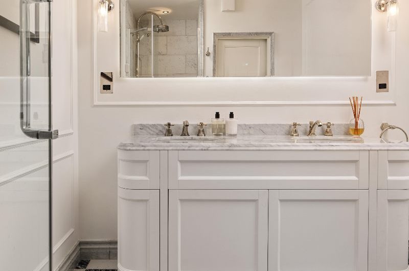 A classic bathroom design with a white double vanity and marble checkerboard flooring.
