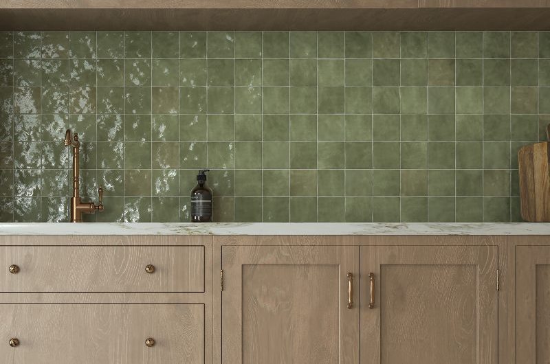 A wood kitchen design with green zellige splashback, marble worktop, and stone flooring.