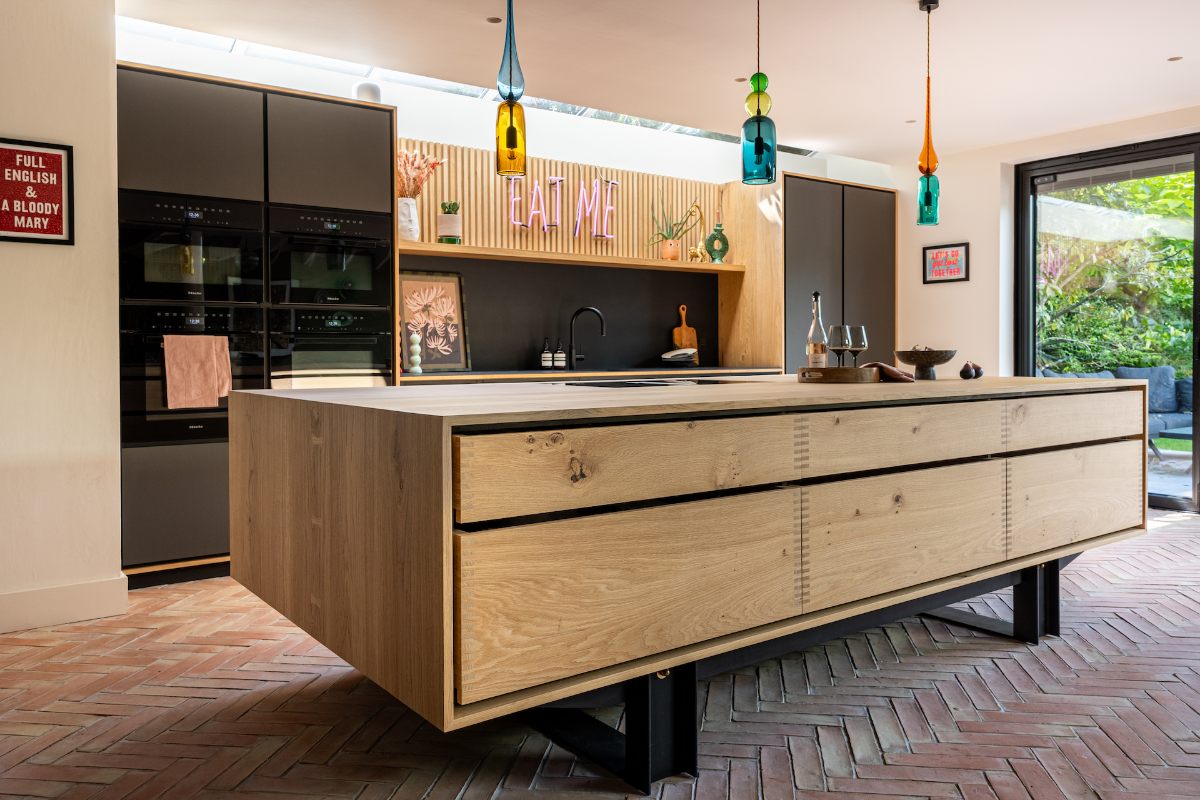 A modern scheme with tall handleless units with built-in appliances, a wood island, and terracotta flooring.