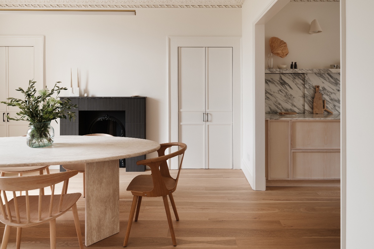An adjoining dining area to the minimalist kitchen with a statement stone table and wooden chairs.
