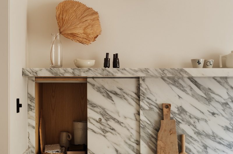 Closeup at the main run of cabinetry with a sliding door in the splashback which conceals a hidden storage nook.
