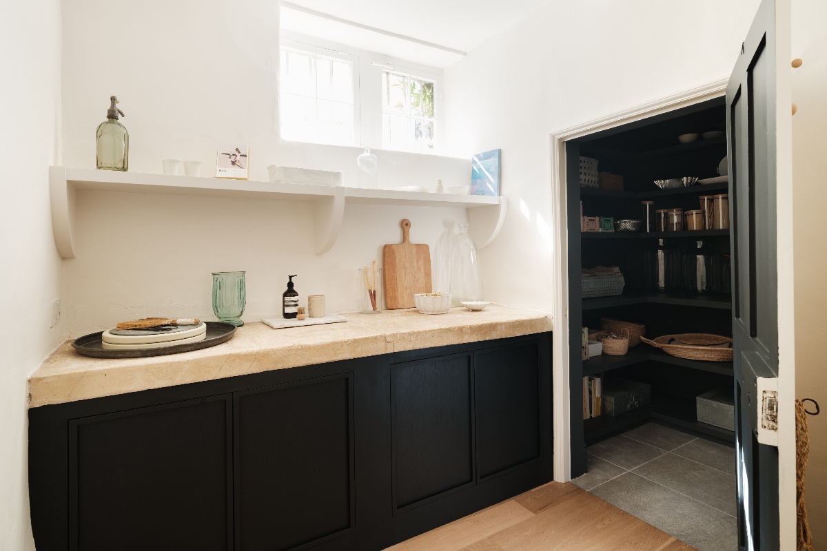 A butler's pantry with extra prep space, a stone shelf, dark base units, and a walk-in pantry.