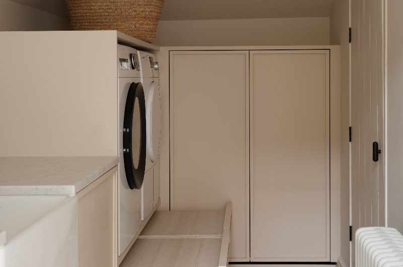A utility room with wood cabinetry, herringbone floor tiles and a butler sink.