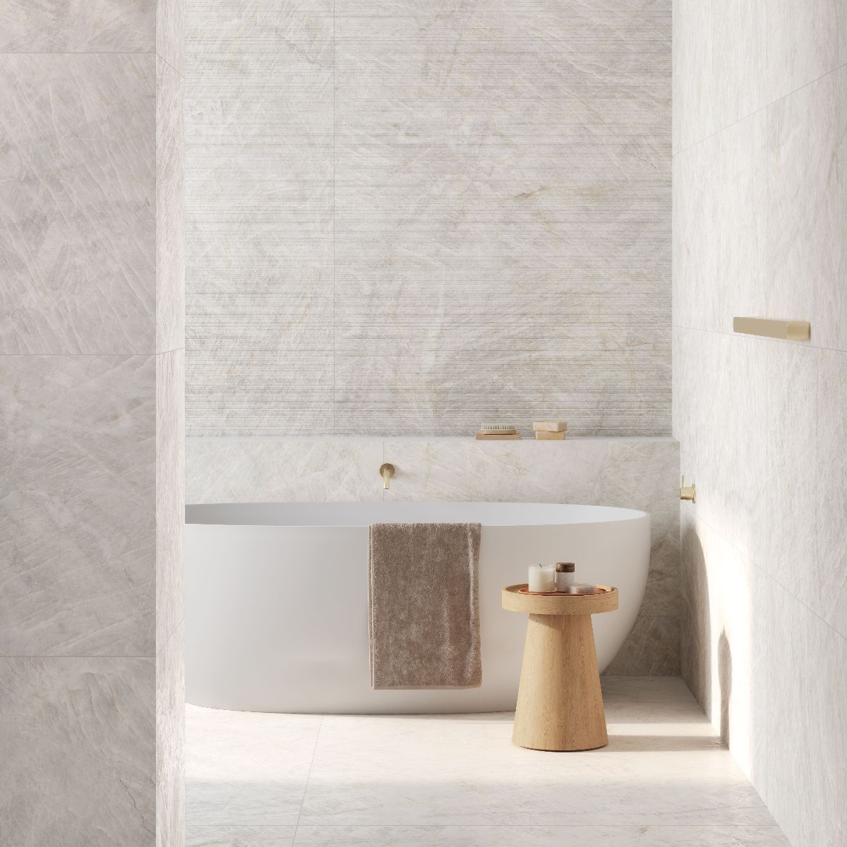 A spa-like space with neutral, fluted wall slabs and matching stone-effect flooring, with a freestanding tub and a wooden stool.
