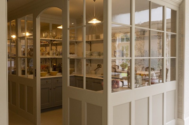 A walk-in pantry design in a Regency house in Hampshire with glazed doors, ample storage, and a secondary sink.
