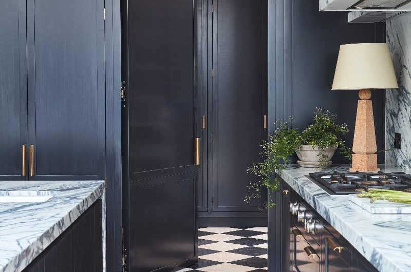 A kitchen design with navy Shaker cabinets and a hidden space behind matching Shaker-style cabinetry.