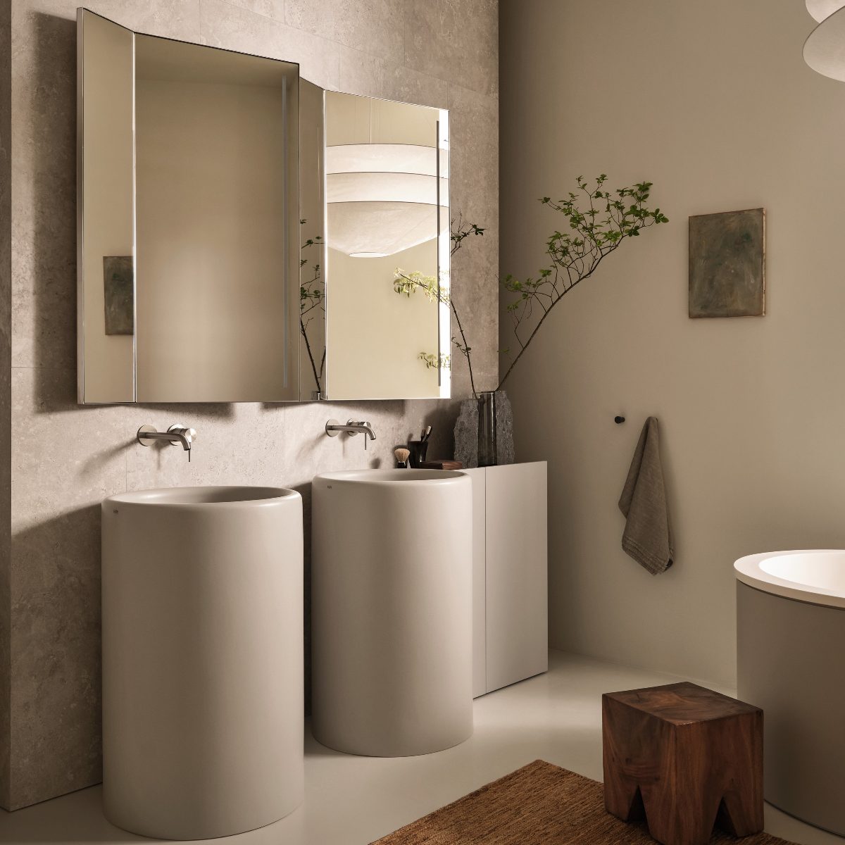 A neutral, spa-like space with tall pedestal basins, mirror cabinets, and rustic decor.