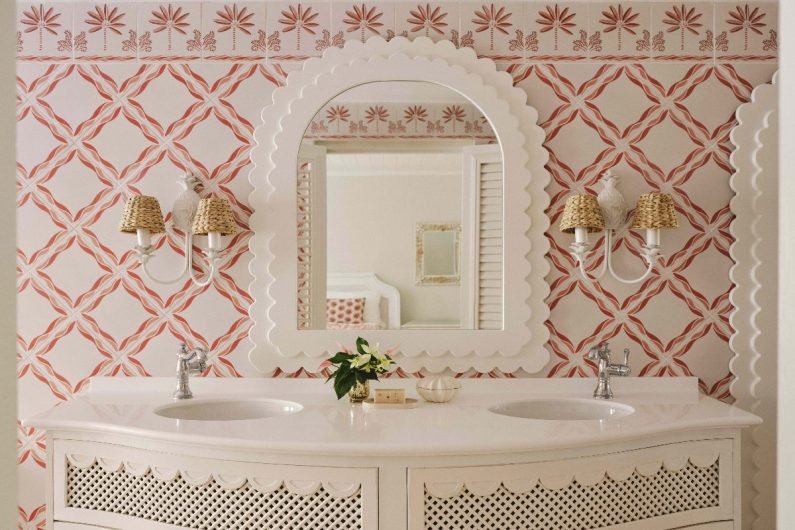 A couple's bathroom with patterned tiles, a double vanity with inset sinks, and a decorative white mirror around it.