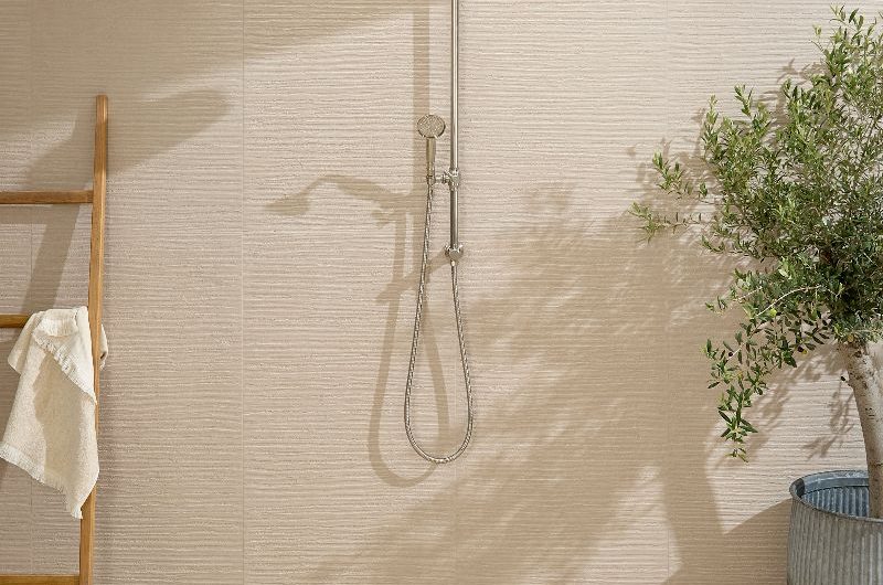 An indoor-outdoor shower zone with extra large wall and floor tiles, in neutral shades and with texture.