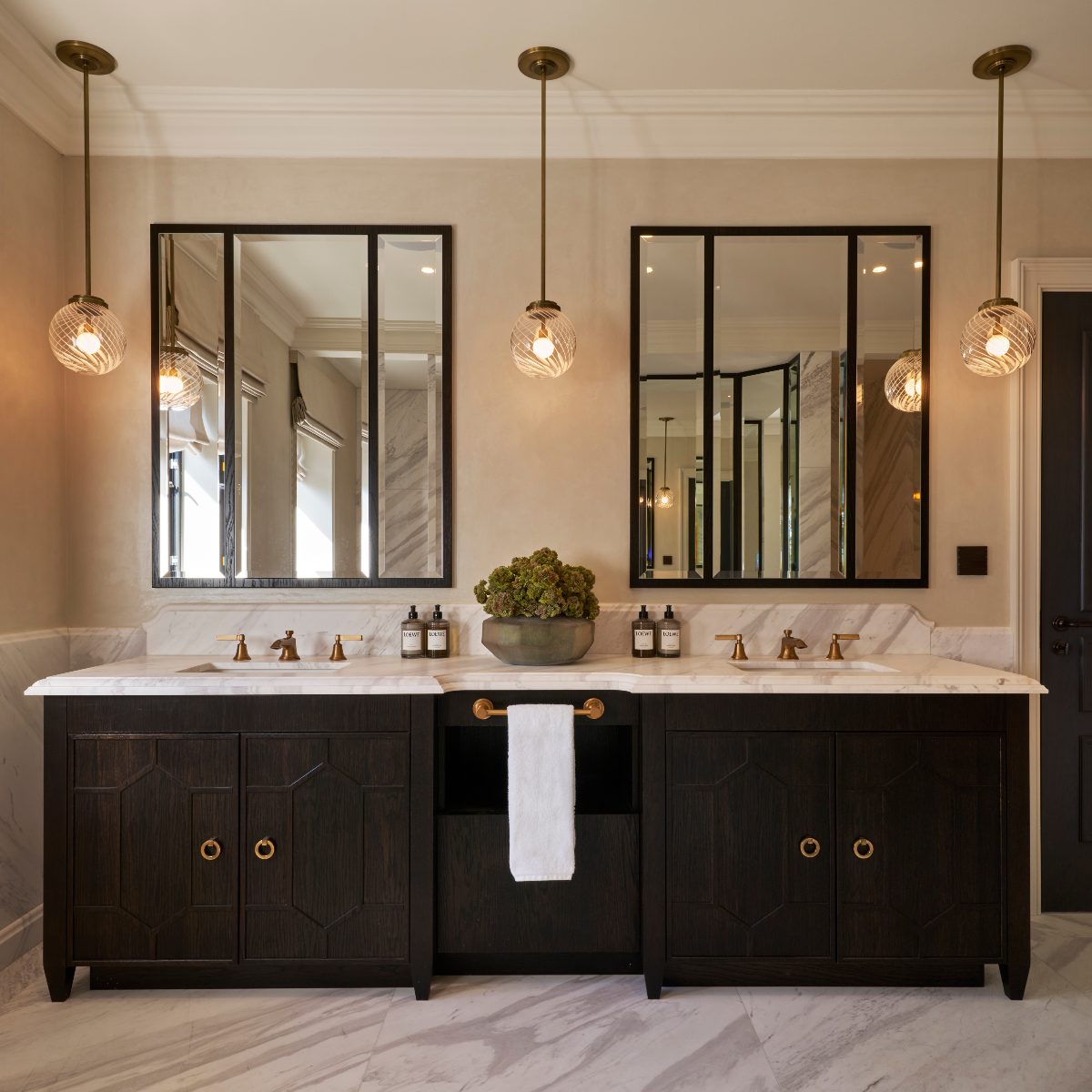 A double vanity with matching sinks, mirrors, and stained oak fretwork doors.