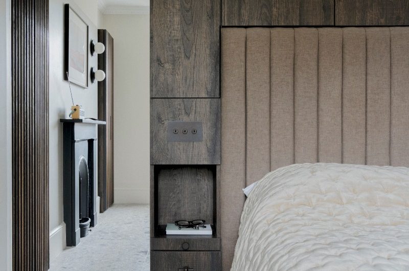 A boutique sleep space with wood panelling, a tall headboard and plush textiles.
