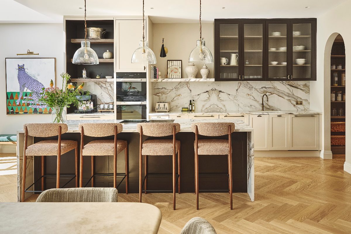 A luxurious kitchen design with a mix of marble, wood and fluted finishes, with a central island with seating and a walk-in pantry.