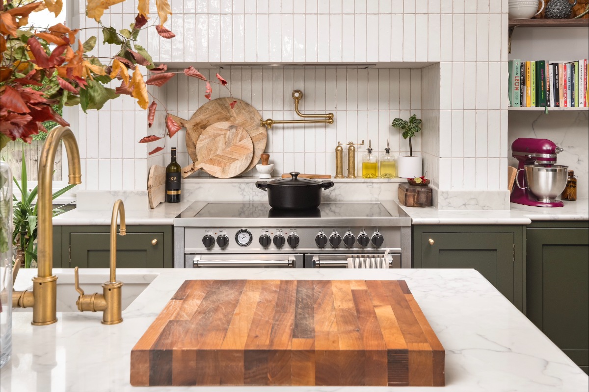 A green kitchen with a cooking zone complete with a range cooker, pot filler tap and concealed extractor.