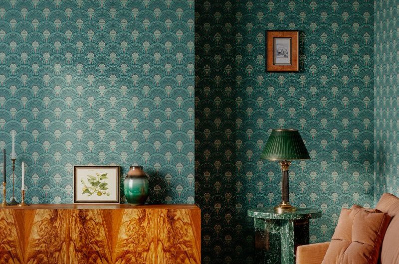 A living room drenched in green tones, with a peach sofa, green marble side tables, and a statement sideboard.