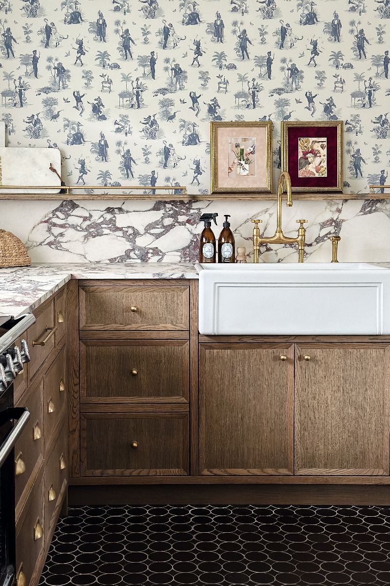 A sink zone with wood cabinets, a butler sink, marble surfaces, and dark flooring.
