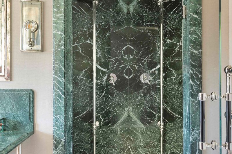 A double shower room with statement green stone surfaces and chrome brassware.