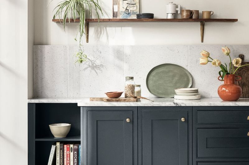 A kitchen design with navy base units, terrazzo flooring, and open shelving.