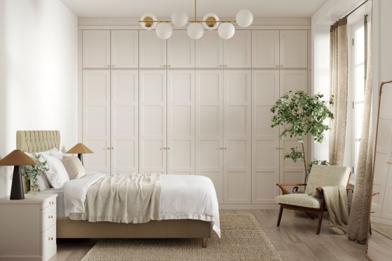 An all-neutral sleep space with tall fitted wardrobes and minimalist decor.