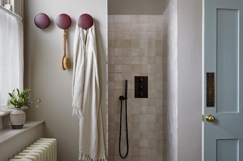 A textured bathroom with a walk-in shower, dark brassware, and zellige tiles.