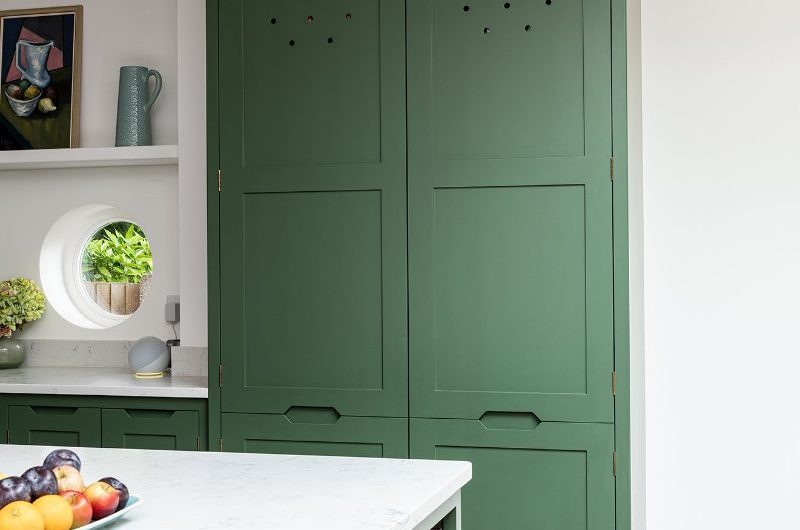 Closeup at a vibrant green floor-to-ceiling dressing unit with decorative vent holes and door panelling.