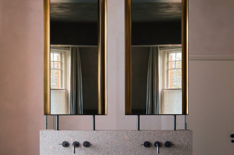 Closeup at a statement vanity zone with oversized concrete basins, sleek black brassware and twin mirrors.