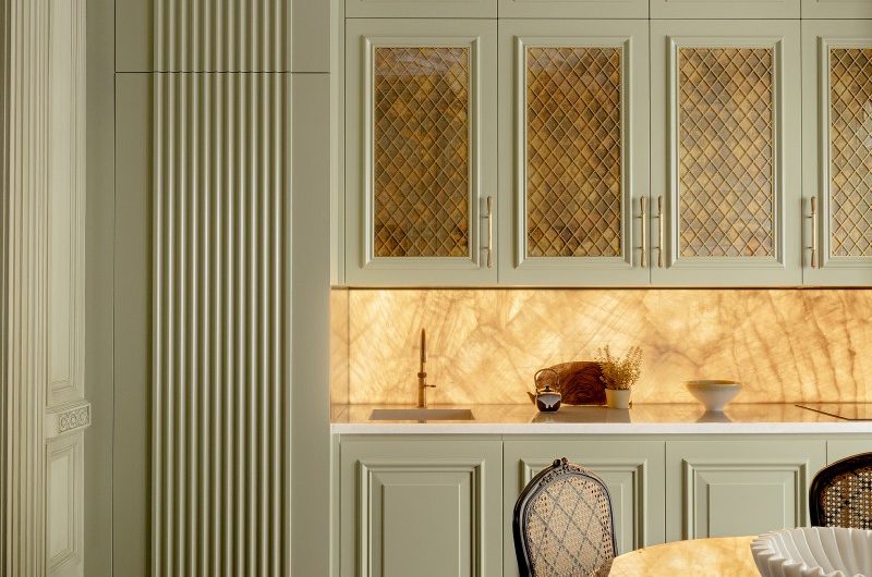 A luxurious kitchen design with detailed cabinetry, backlit splashback, and decorative trim moulding.