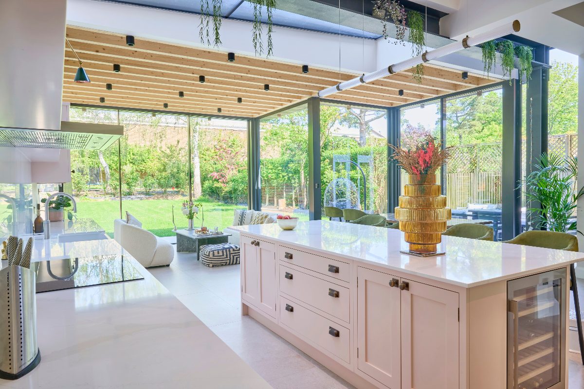 View of the pink kitchen island overlooking the wide expanse of glazing into the garden.