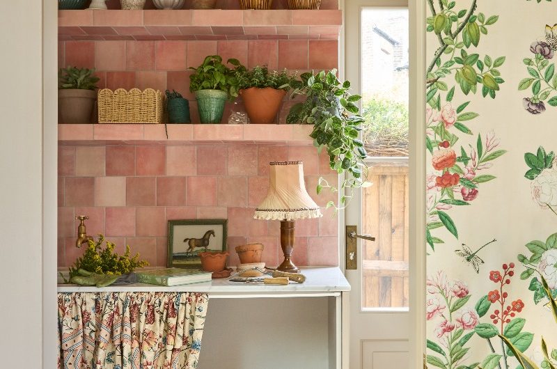 A utility room with a floral dog bed concealed by a curtain skirt, with pink zellige tiles, and tiles open shelves.
