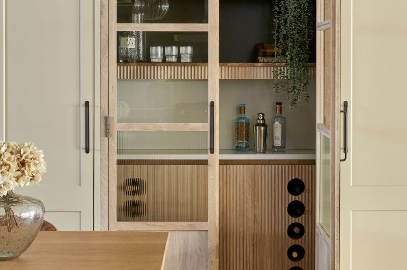 A walk-in pantry with reeded base units, fluted shelving and glass doors.