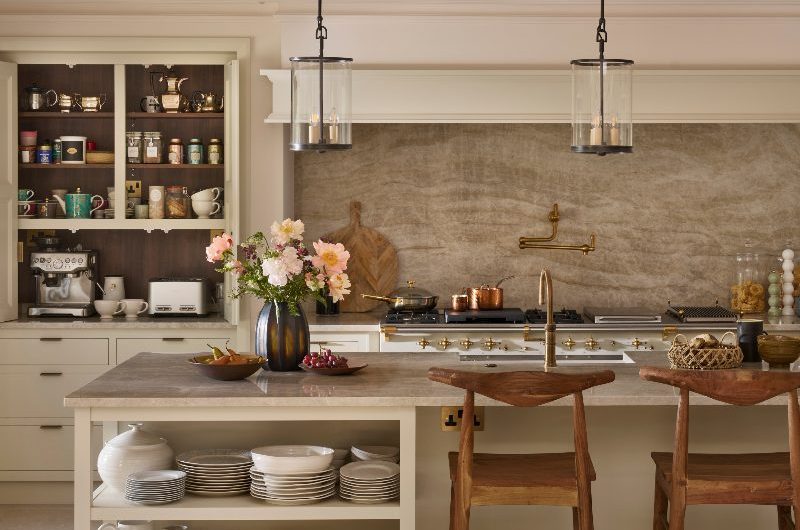 A timeless kitchen design with neutral cabinetry, stone flooring, a central island with open shelving and seating, and a statement cooking zone.