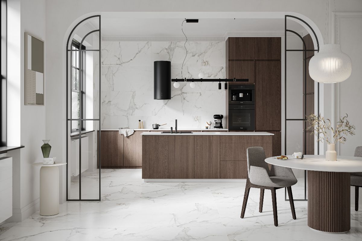 A modern kitchen with extra large floor and wall tiles with a marble effect, wood cabinetry, and black fittings and appliances.