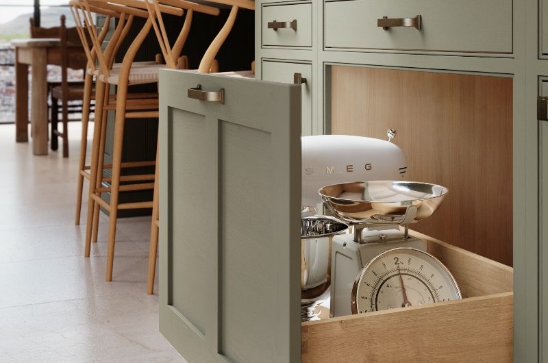 Closeup at a green island with a pull-out drawer housing small appliances.