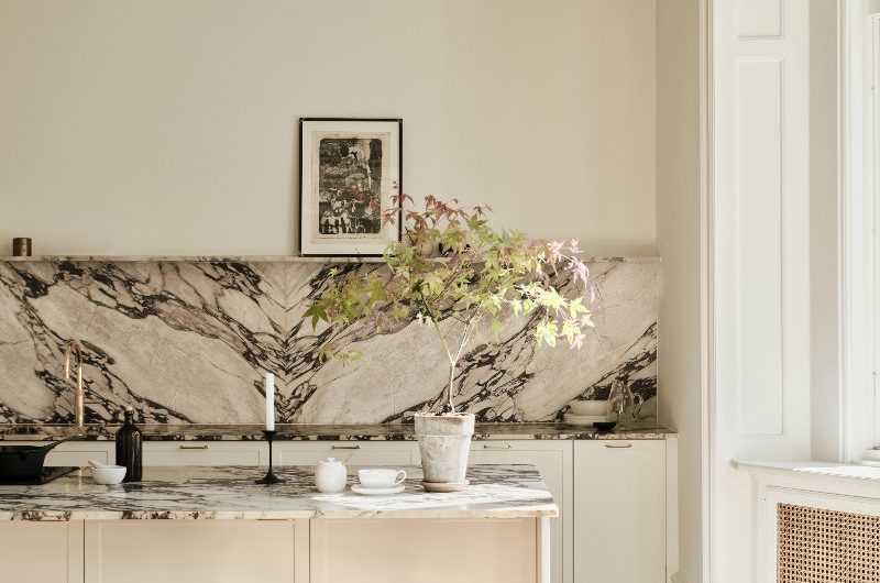 A calm, modern scheme in Copenhagen with cream cabinetry, calacatta viola marble, and a painted green ceiling.
