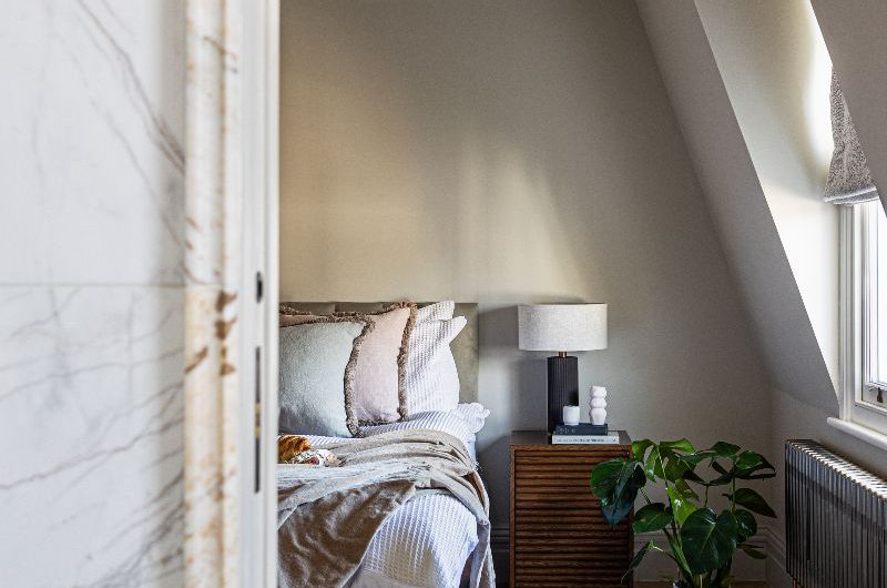 A calm and minimalist sleep space with chevron flooring, fluted bedside tables, and tactile linen.