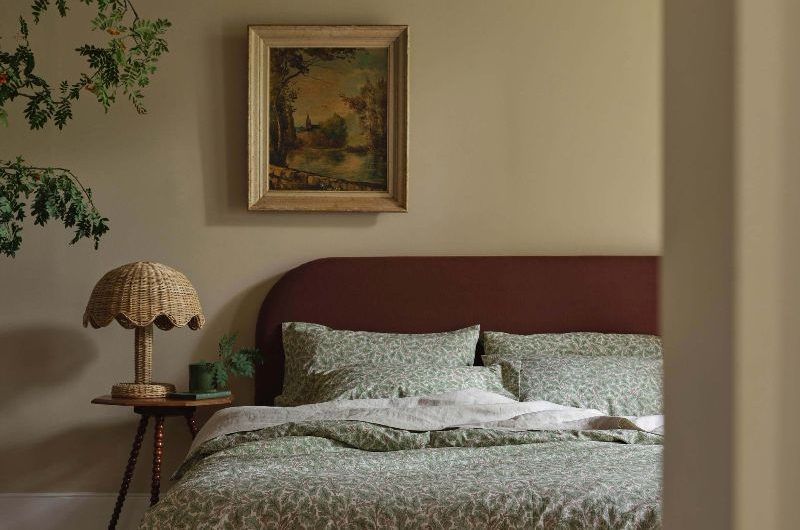 A whimsical bedroom with nature-inspired bed linen, rattan bedside lamp, and wall art.