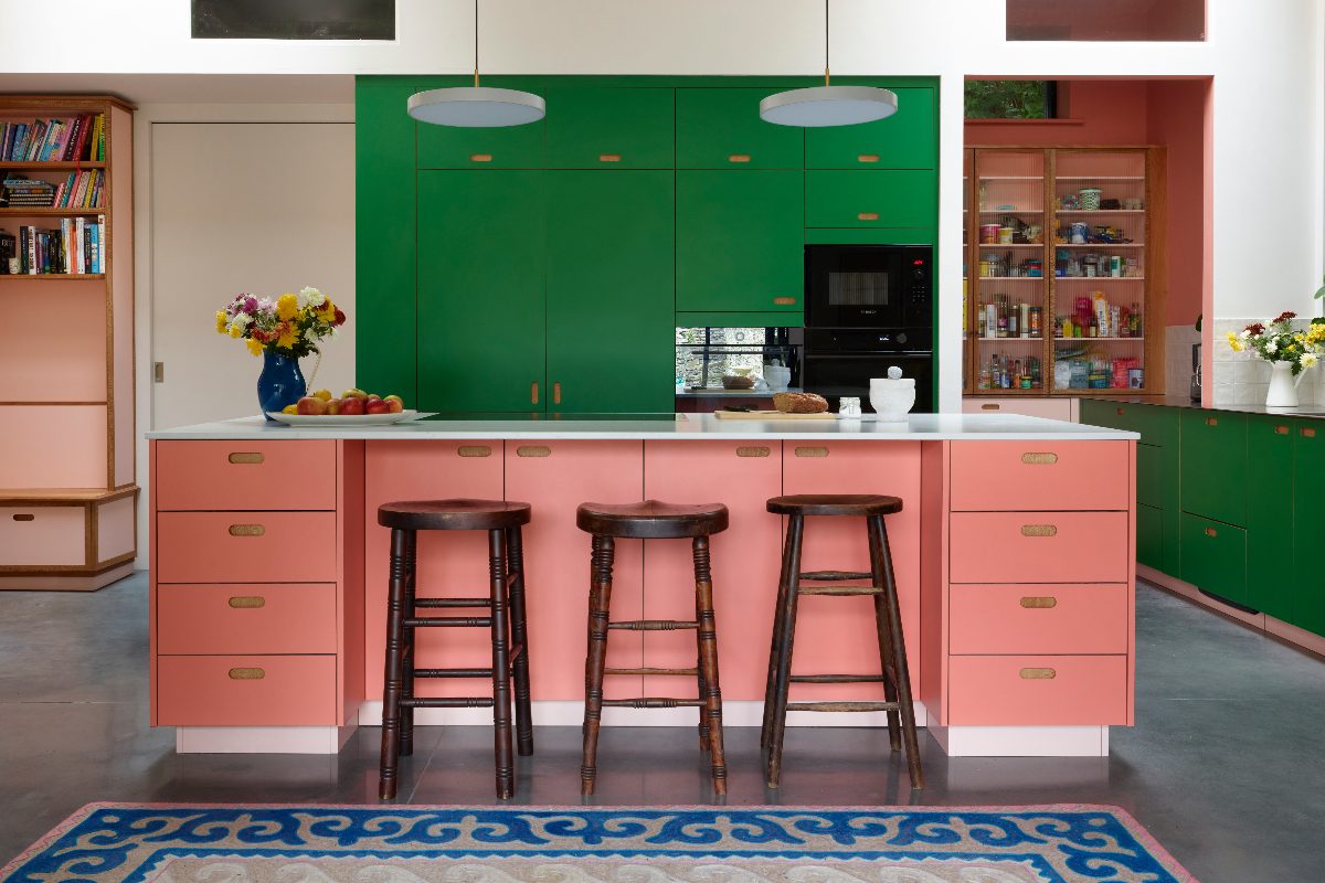 A colourful scheme with vibrant green on the main cabinetry run, with a coral walk-in pantry and a matching island with seating.